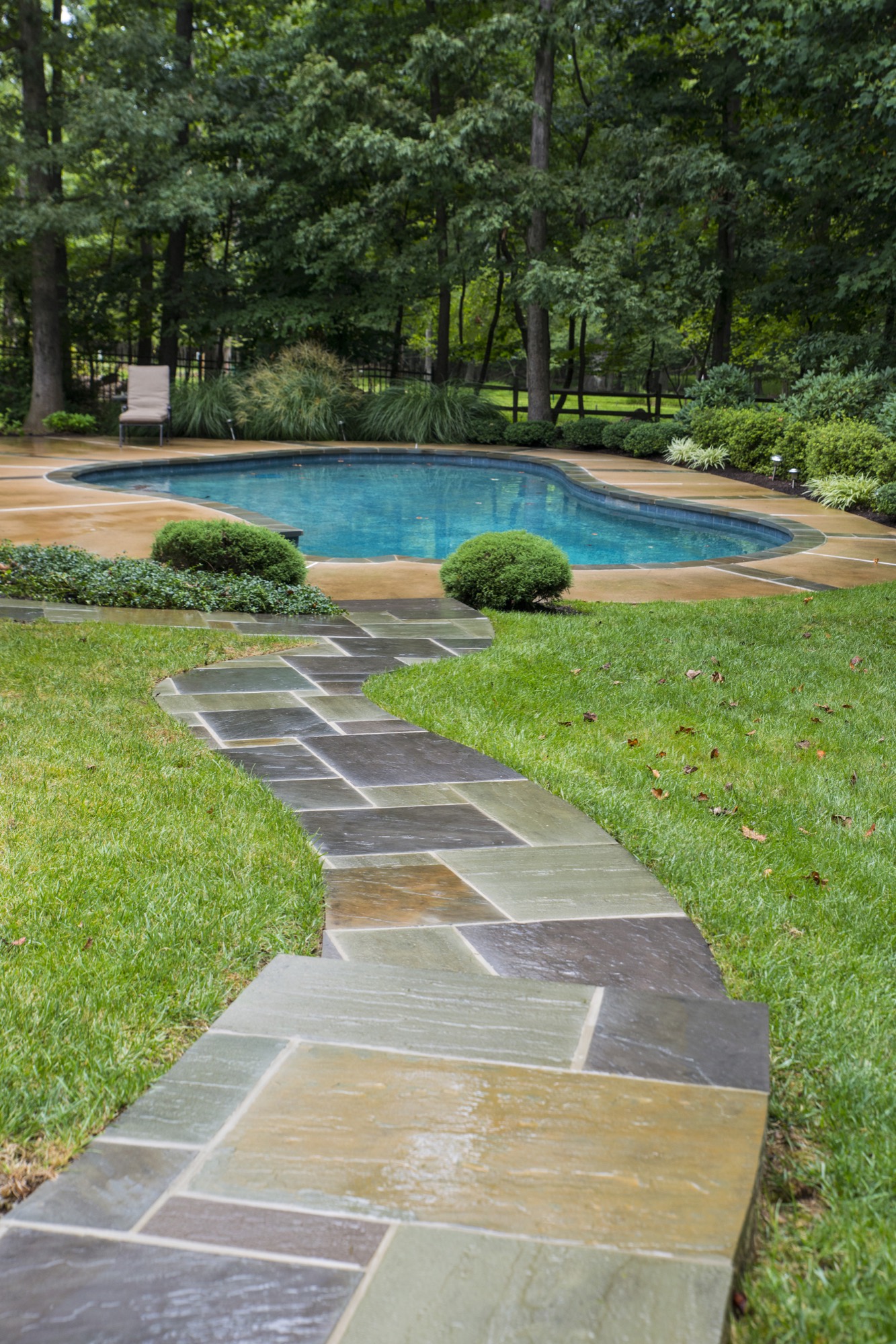 Flagstone path leading to a pool across a manicured lawn in Northern Virginia