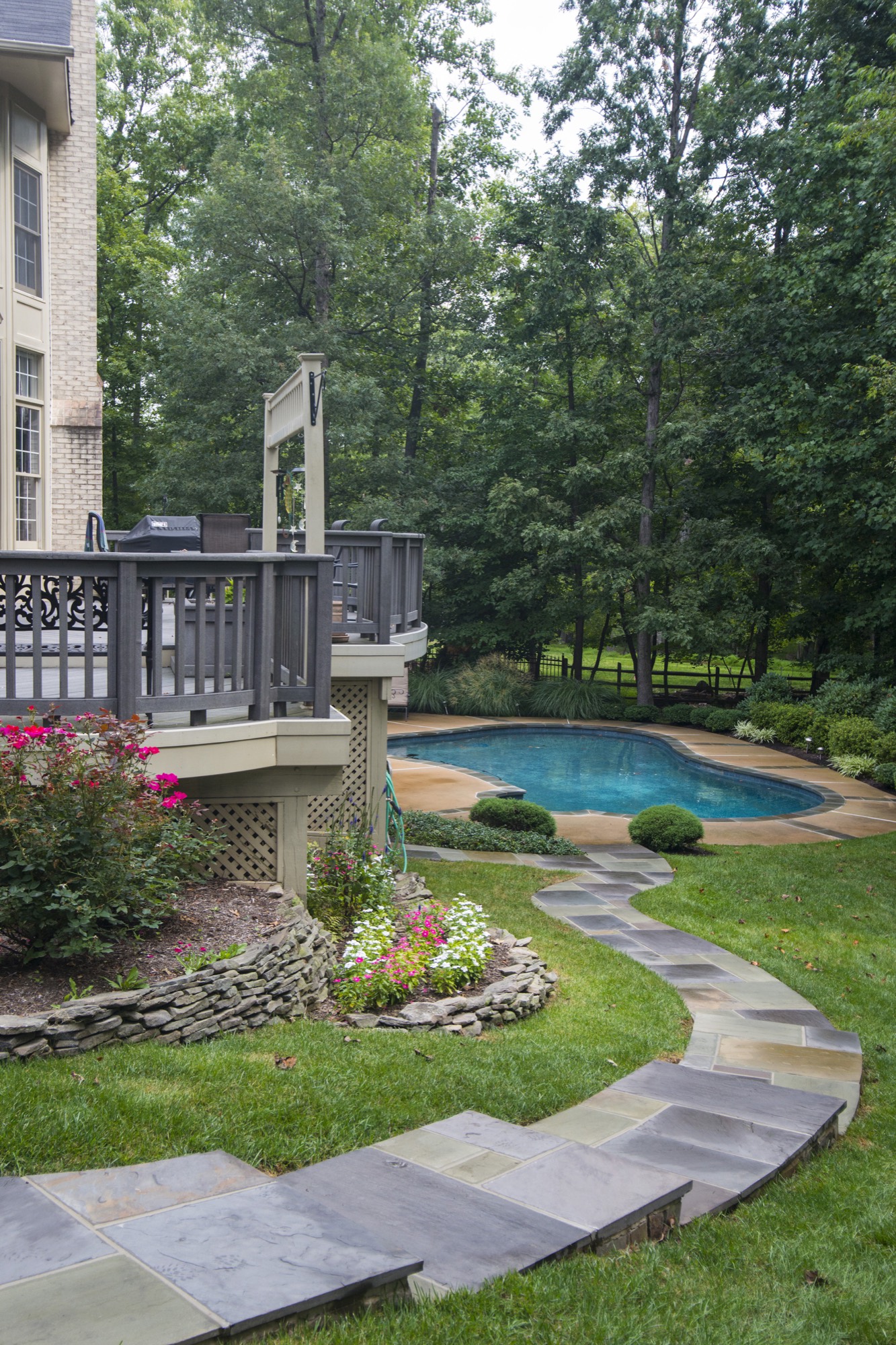 Backyard with deck, pool, flagstone steps and stone borders in Northern Virginia